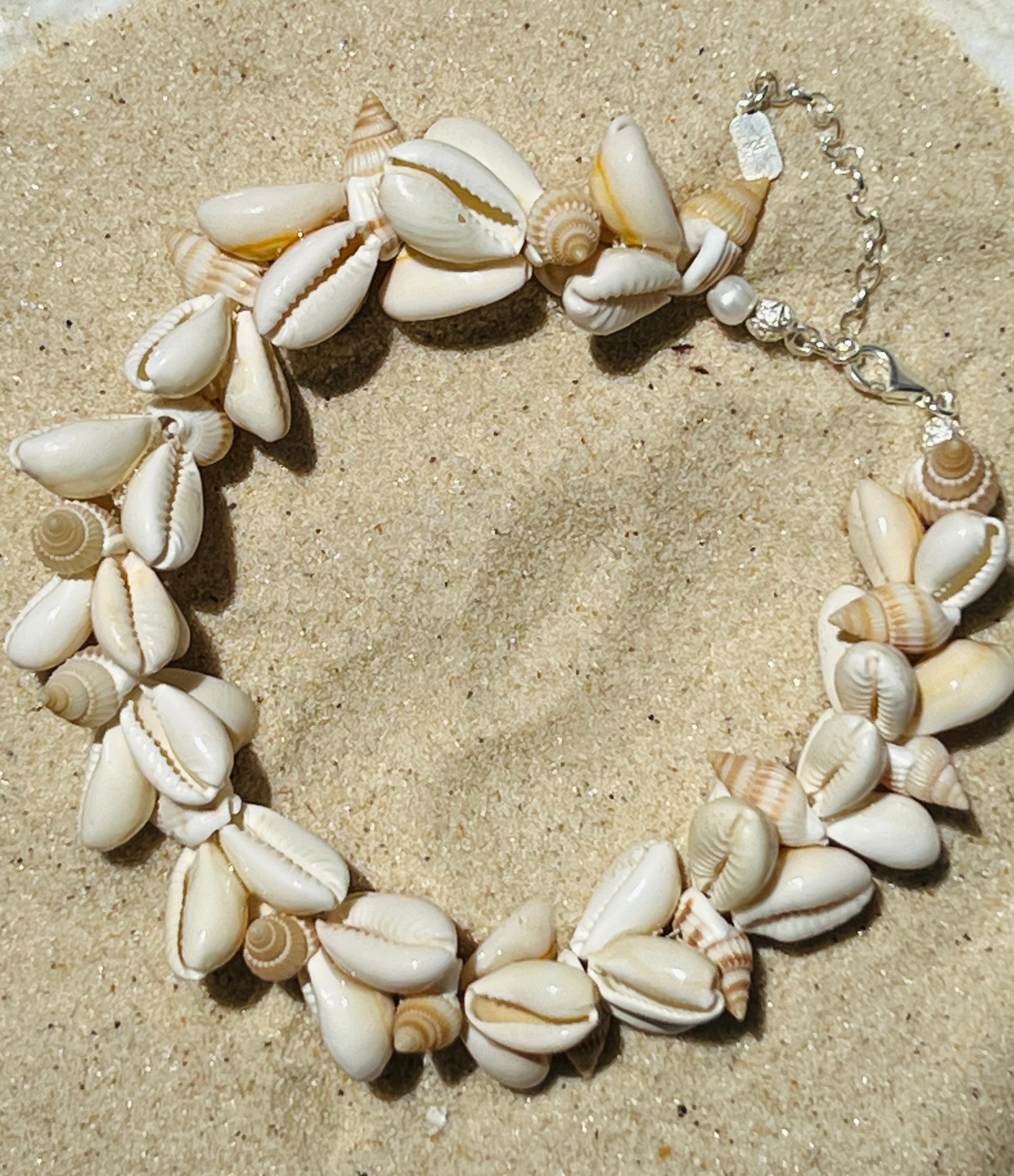 Cowrie shell and pearl anklet displayed on the sand