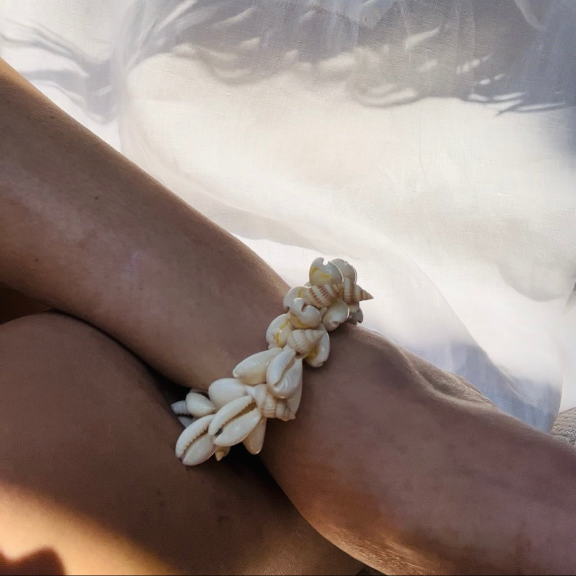 Cowrie shell and pearl anklet displayed on a model's wrist