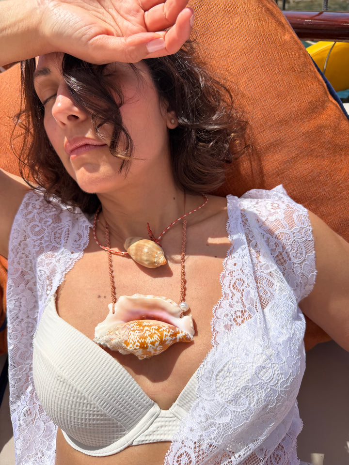 Woman wearing a white bikini top and a lace open top wearing the Cowrie Helmet Necklace