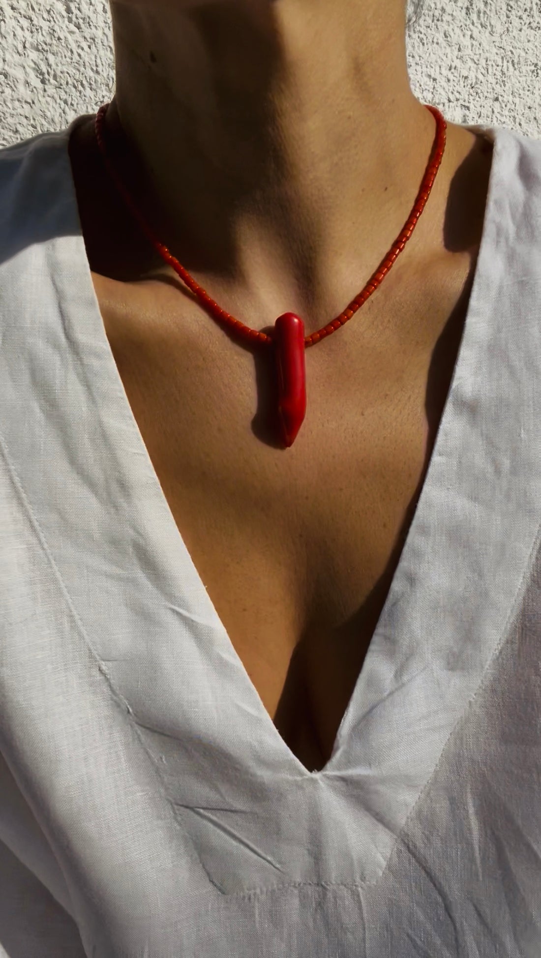 Lifestyle view of the red coral necklace styled with a white linen kaftan.