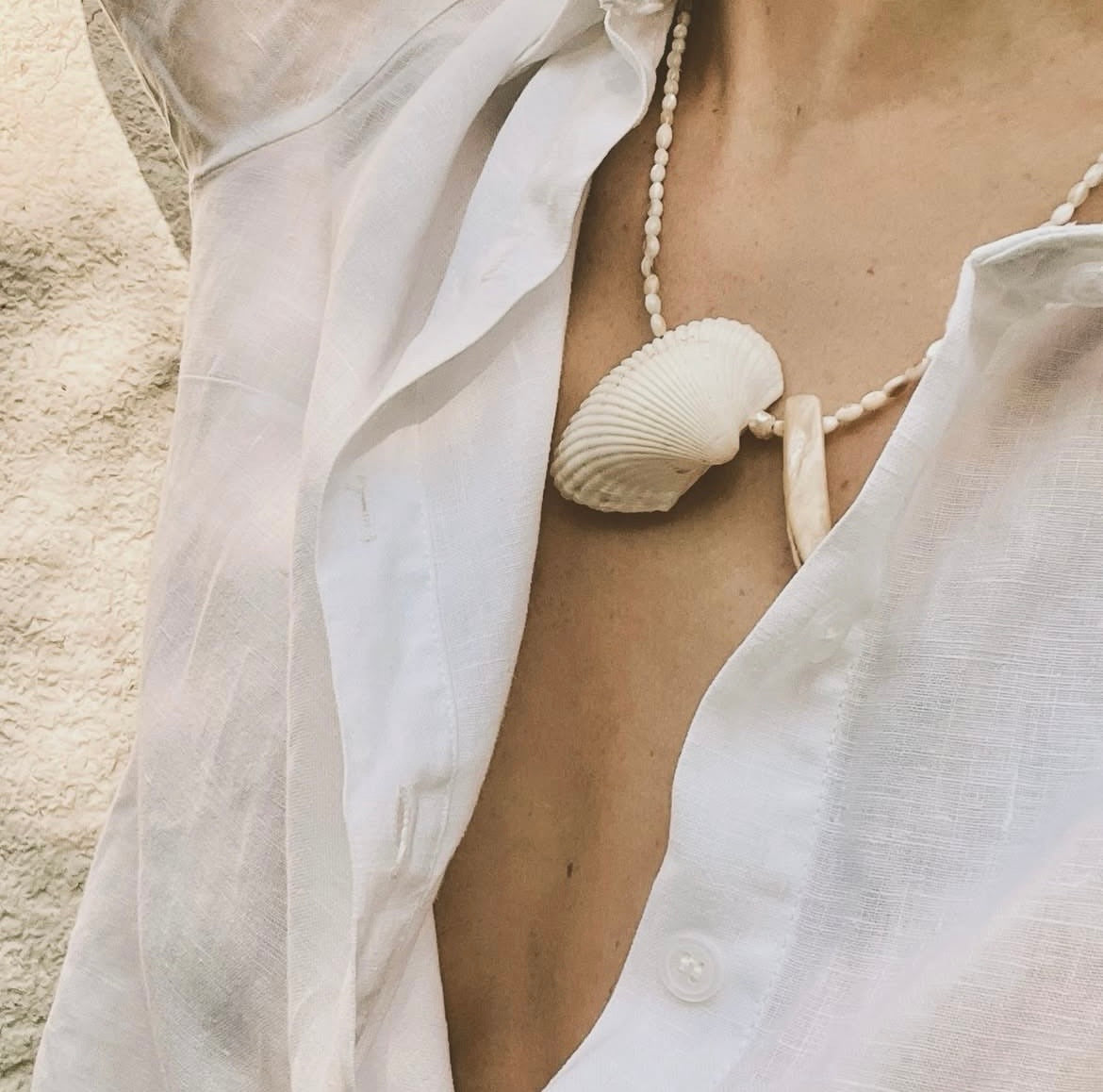 Close-up lifestyle view of the Sirinite Oval necklace, styled with an open white linen shirt for a refined, coastal-boho look.