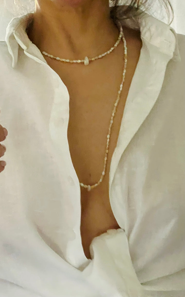 Person wearing a pearl necklace with a white shirt