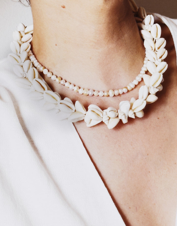 Close-up of a person wearing the cowrie shell necklace 