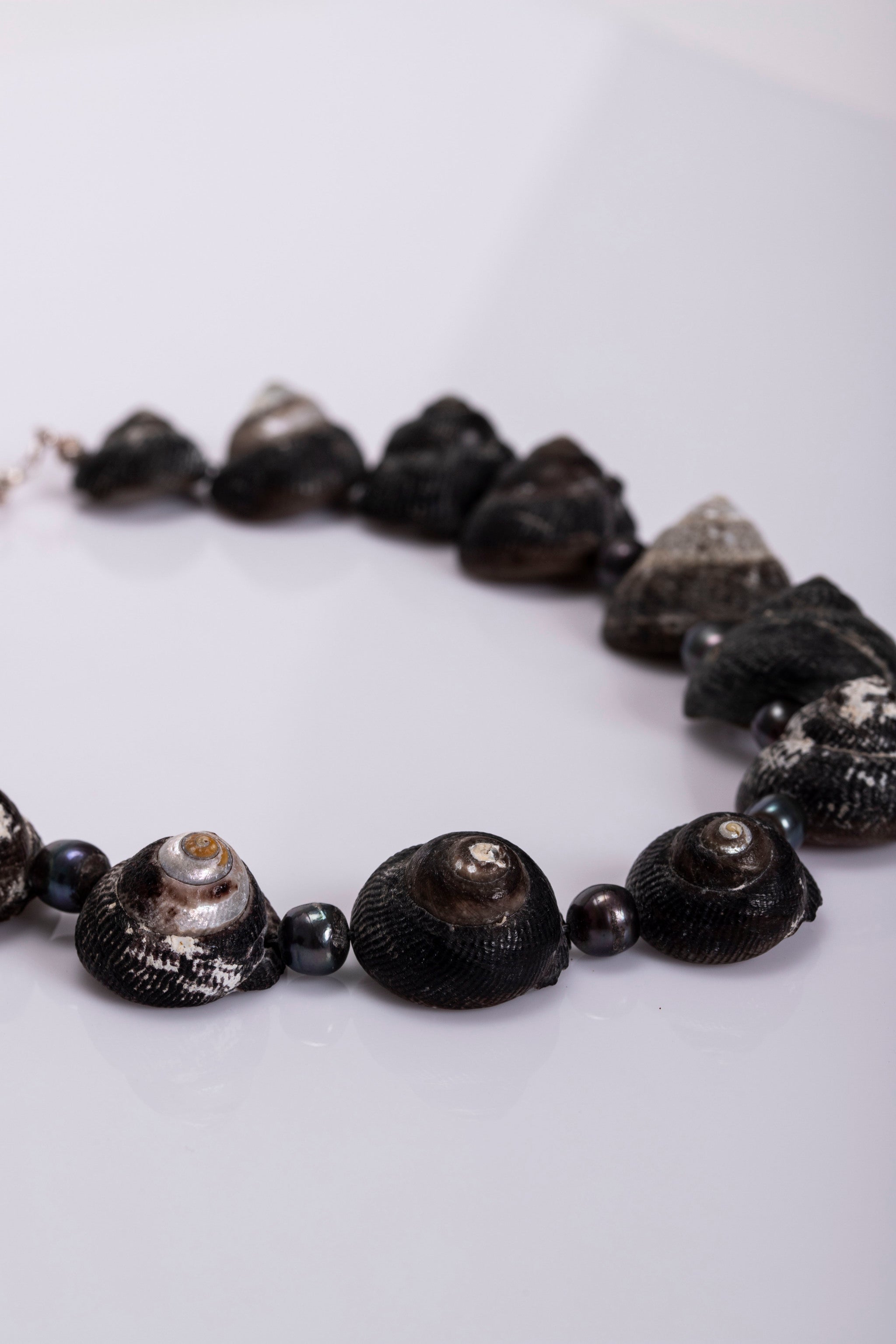 Close up of a necklace made of pearlized Umbinium and black pearls.