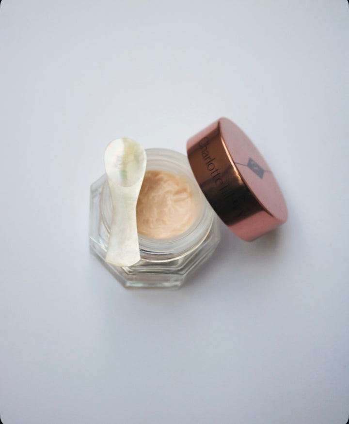 Skincare product in a hexagonal jar with a rose gold lid and a pearl spoon on a white background