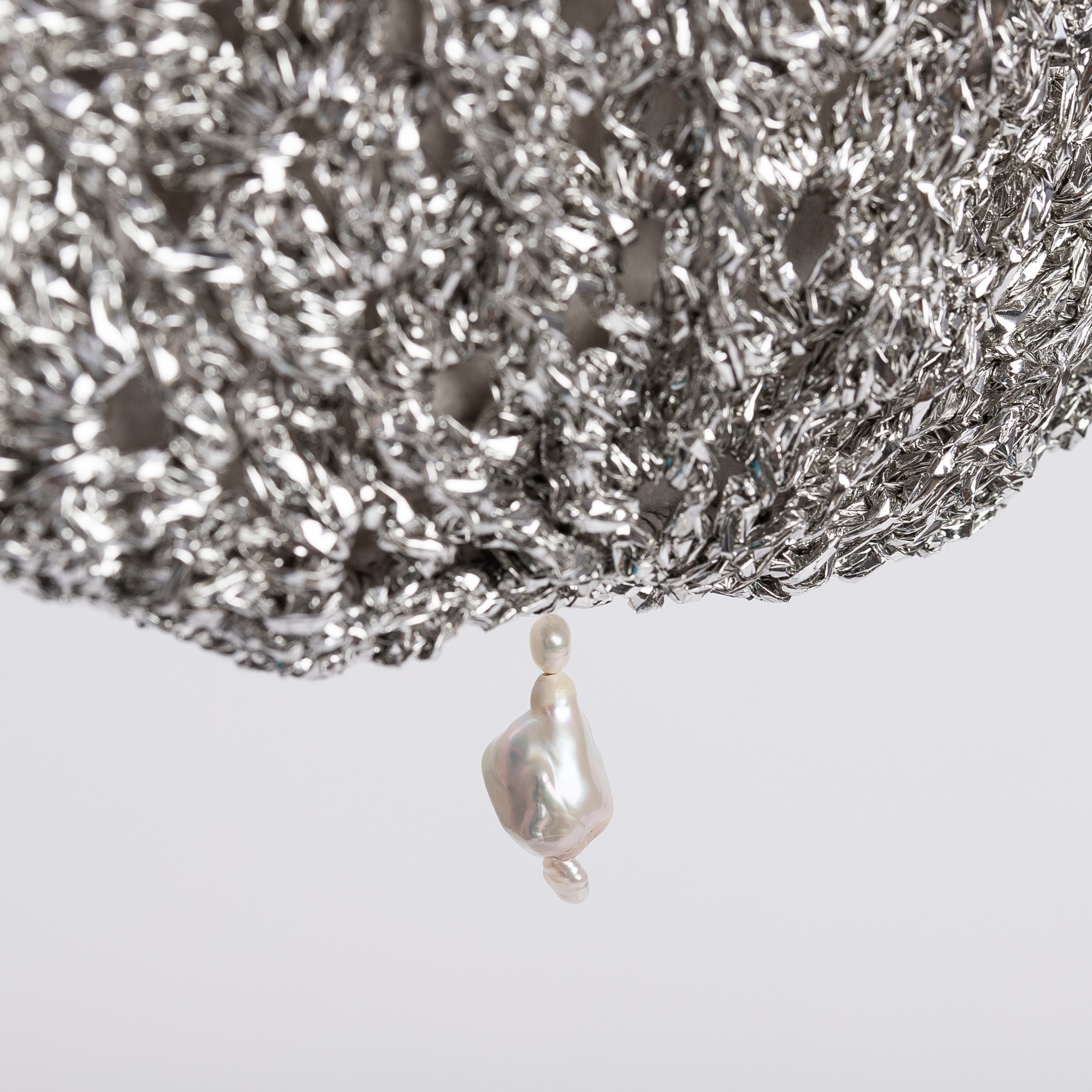 Close-up of the artisanal silver crochet texture and iridescent pearl drop.