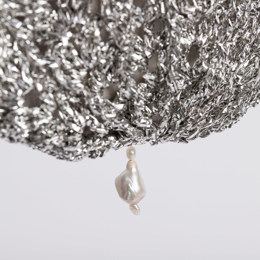 Close-up of the artisanal silver crochet texture and iridescent pearl drop.