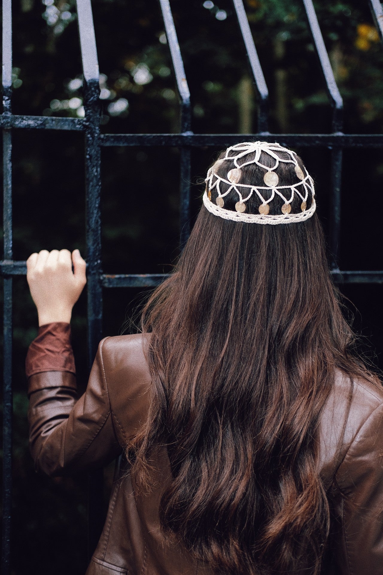 Rear view of the crochet shell headpiece styled with a leather jacket, showcasing its fit and placement on long hair.